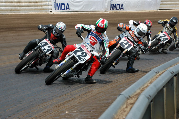 A group of people on motorcycles racing down the track.