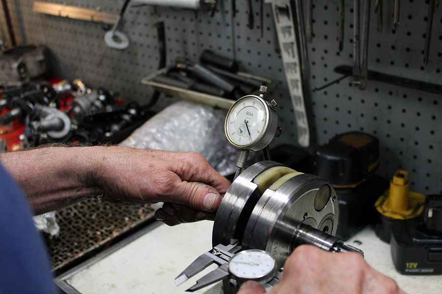 A person working on a metal object with a measuring tool.