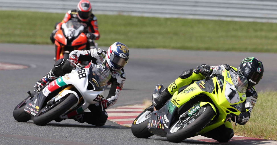 A group of people on motorcycles racing down the track.